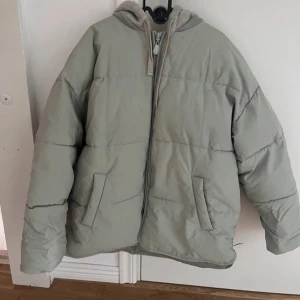   pufferjacka från ASOS DESIGN - Säljer en snygg och bekväm pufferjacka från ASOS DESIGN. Jackan har en dragkedja framtill och en mysig huva. Perfekt för kyliga dagar och ger en avslappnad look. Passar bra till både vardag och utflykter. 🧥