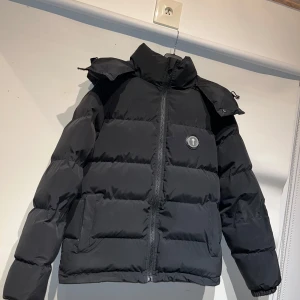 Svart pufferjacka från trapstar - Säljer en svart pufferjacka från Trapstar i mycket bra skick. Jackan har en dragkedja framtill och en broderad Trapstar-logga på ryggen. Den är perfekt för vintern med sin varma och quiltade design. Storleken är normal och den har långa ärmar. Grym för både vardag och chill häng! 🖤 kan gå ner pris vid snabb affär 