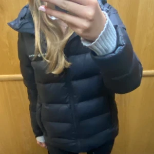 Svart dunjacka från Sail Racing - Säljer en snygg svart dunjacka från Sail Racing. Jackan är perfekt för kalla dagar med sin pufferstil och långa ärmar. Den har en praktisk dragkedja och en mysig huva. Perfekt för både höst och vinter! 🖤OBS! (jackan har någon defekt som jag kan skicka bild på vid intresse)💓strl 170 (ungefär en S) pris kan diskuteras