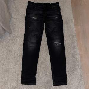 Säljer ett par svarta slim fit jeans från Jack & Jones i storlek 158/13Y. De har en cool, sliten look med diskreta revor och är perfekta för en såkallad grisch stil. Passar både till vardags och festliga tillfällen. Jeanslappen har gått av en liten bit (Se bild 5) Skriv vid minsta lilla fundering✍️😀✅ 