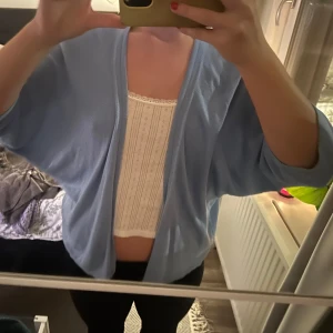 Ljusblå kofta - Säljer en superfin ljusblå kofta i mjukt material. Den är öppen framtill och har en avslappnad passform. Passar perfekt över en topp eller klänning för en casual look. 