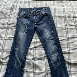 Blå jeans från Dsquared2 knappt andvända  - Säljer ett par snygga blå jeans från Dsquared2 i storlek 30. De har en cool distressed look med slitningar och en klassisk femficksdesign. Perfekta för en avslappnad stil med en touch av edge. Passar både till vardags och fest! 