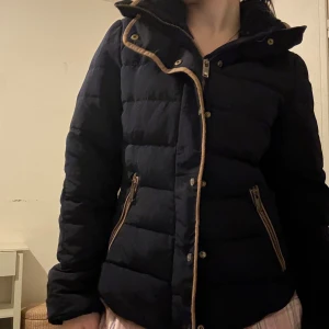 Svart pufferjacka från ZARA - Säljer en snygg svart pufferjacka i mycket bra skick. Den har en dragkedja och knappar framtill, samt praktiska fickor med dragkedjor. Perfekt för kyliga höst- och vinterdagar. Jackan är långärmad och har en skön passform som håller dig varm och bekväm.