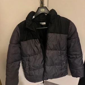 Svart och grå pufferjacka från hm - Säljer en snygg svart och grå pufferjacka från hm. Jackan har en dragkedja framtill och är perfekt för kalla dagar. Den är i bra skick och har en cool logga på ärmen. Perfekt för vintern! Märken som syns på sista bilderna🖤
