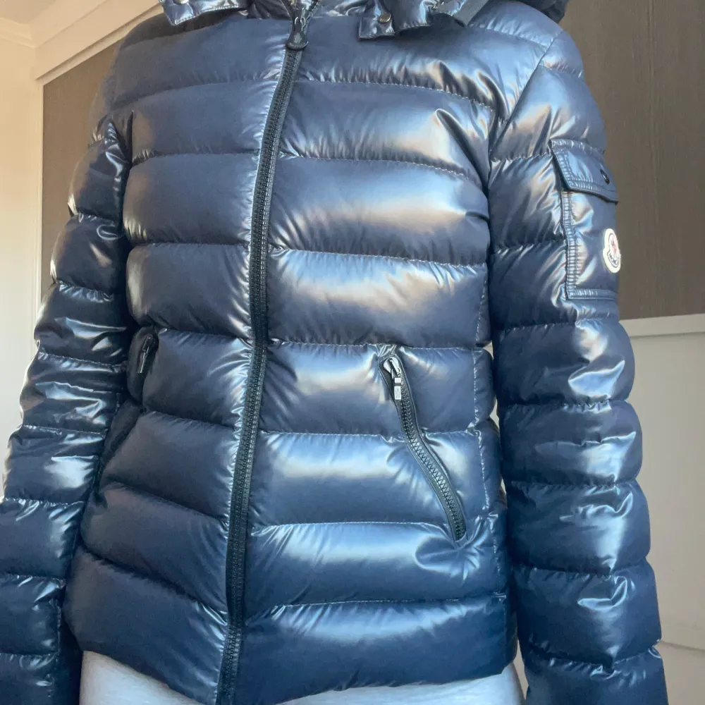 Säljer en snygg mörkblå pufferjacka från Moncler i mycket bra skick. Jackan har en glansig finish och är perfekt för kalla vinterdagar. Den har en dragkedja framtill och praktiska fickor med dragkedjor. Perfekt för både vardag och festliga tillfällen! Modellen är bady och passar xs💗. Jackor.