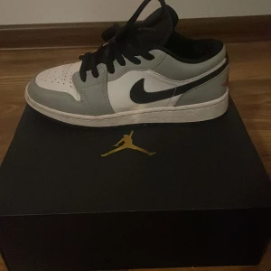 Nike Air Jordans Smoke Grey Low - Säljer ett par Nike Air Jordans i färgen Smoke Grey. De är i lågt utförande med svart snörning och en enkel design. Storlek 36. Skorna är i mycket bra skick och kommer med originalkartong. Endast använda ett fåtal gånger. Köpt från merchsweden.                                  Nypris på hemsida: 4 499.                                              Priset går att diskuteras