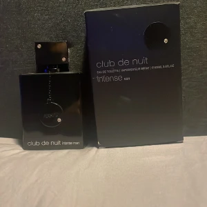 Club de Nuit Intense Man Eau de Toilette - Säljer en elegant och intensiv herrparfym från Armaf, Club de Nuit Intense Man. Flaskan är svart och stilren med en glansig finish och dekorerad med små kristaller. Den rymmer 105 ml av en doft som är både maskulin och förförisk. Perfekt för kvällar ute eller speciella tillfällen. Kommer i originalförpackning.