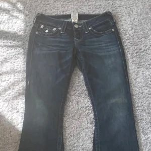 Mörkblå jeans med broderade fickor - Midjemätt 38 ca Innerbenslängd 79💕💕Säljer ett par snygga mörkblå true religion  jeans med coola broderade detaljer på bakfickorna. De har en klassisk femficksdesign och en knappgylf. Perfekta för både vardag och fest!