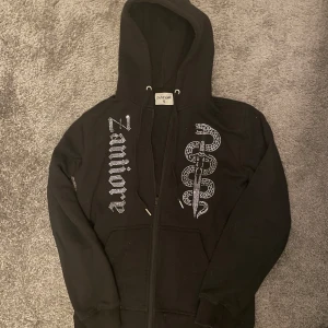 Svart rhinestone zip från Zanitore - Säljer en svart rhinestone zip hoodie från zanitore. Skick 7/10. 