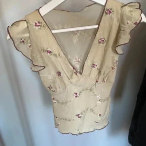 Mesh topp - Säljer en mesh topp med volangdetaljer vid ärmarna och en v-ringad design. Har inga hål eller lösa trådar så skulle säga bra skick! 🔴Kan sänka pris vid snabb affär!🔴Kom dm för funderingar eller fler bilder 💗☺️