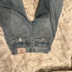 True Religion Jeans - Ett par ljusblåa true religion jeans. Dem är i storlek 25 och mid rise bootcut. Allmänt bra skick ändats lite slitningar i ändarna då dem varit för långa. 