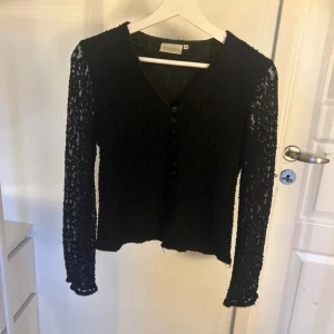 Spetströja med knappar  - Cool och unik spetstopp med knappar som är lagom lång (inte croppad)  Spetsmönstret är väldigt fin och kan nästan ge en illusion av glitter  Det är endast armarna som är ”genomskinliga”  Storlek 40 men skulle mer säga att den passar S-M