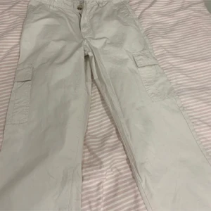 Beige Cargobyxor - Säljer ett par beige cargobyxor i mycket skick. De har flera praktiska fickor på sidorna och bak. Dom sitter framför allt bra runt midjan och är riktigt sköna. Har aldrig haft dom ute utan dom har bara testats.