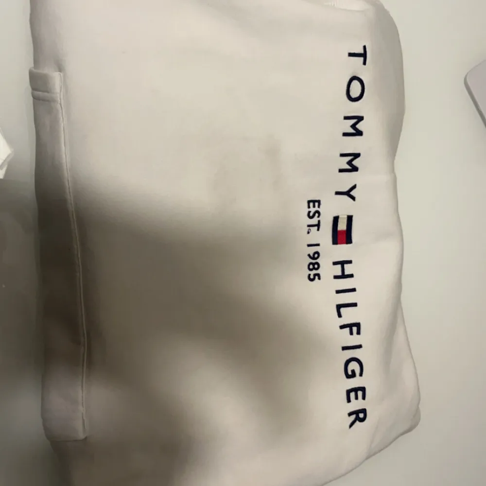 Säljer en snygg vit hoodie från Tommy Hilfiger i storlek L. Den är gjord av ekologisk bomull och har en klassisk design med logotypen tryckt på framsidan. Perfekt för en avslappnad stil och passar till alla årstider. 🕶️. Tröjor & Koftor.