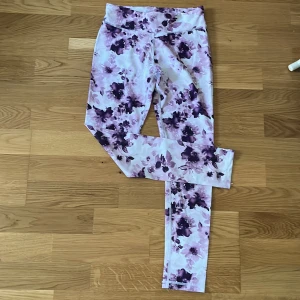 Blommiga leggings från Energetics - Säljer ett par snygga blommiga leggings från Energetics i storlek 146/152. De har ett vackert mönster i lila och rosa nyanser på en vit bakgrund.Materialet är mjukt och stretchigt för bästa komfort.