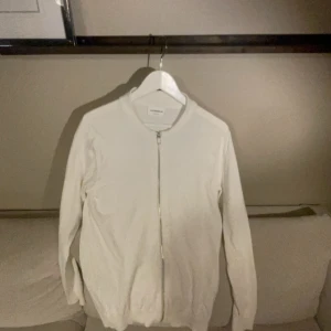 Vit tröja med dragkedja från Lindbergh - Säljer en stilren vit tröja från Lindbergh i relaxed fit. Den har en praktisk dragkedja framtill och är perfekt för både vardag och fest. Tröjan är långärmad och gjord i ett mjukt material som känns skönt mot huden. Passar perfekt till höst och vår! Har aldrig används!!! Helt ny skick 10/10 storlek S passar M