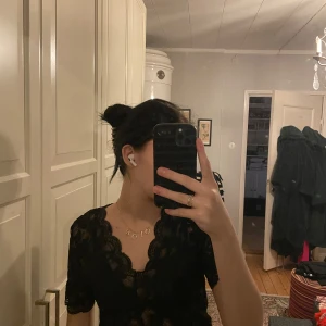 Svart spetsblus - Säljer en elegant svart spetsblus med korta ärmar och vacker blommig design. Perfekt för festliga tillfällen eller en utekväll. Blusen har en fin passform och ger en sofistikerad look. Passar bra till både kjol och byxor.