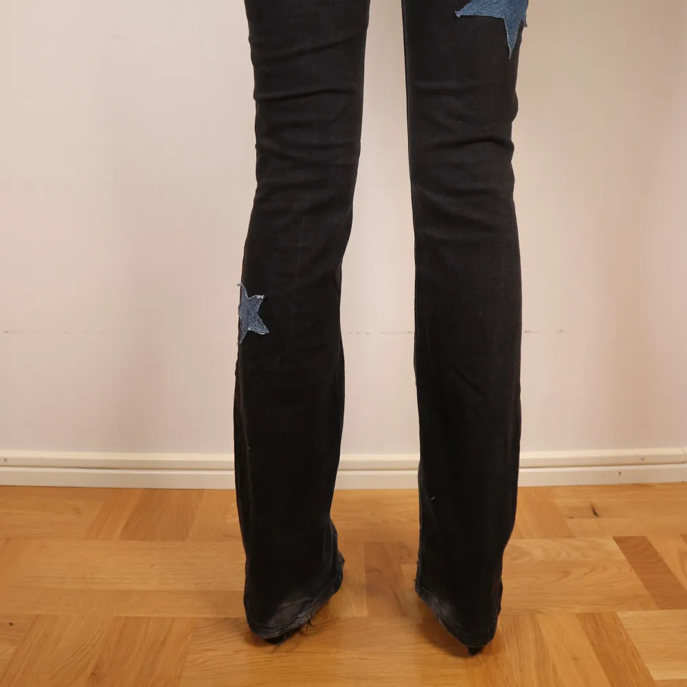 Snygga svarta jeans med coola blå stjärnor på benen. De har en bootcut stil och är från märket GRUNT. Designen är noggrant utvald och sydd för hand. Måtten är: Midja: 34cm, Innerben: 79cm, Ytterben: 104cm . Jeans & Byxor.