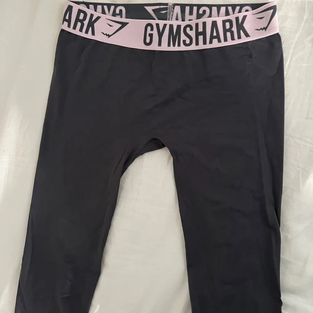 Låg midjade gymshark leggings i grå färg med ljusrosa band. Hellånga. Ingen söm framtill eller baktill. Fint skick. . Sportswear.