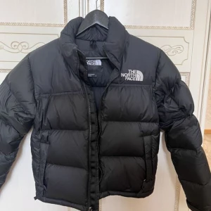 Svart pufferjacka från The North Face - ÄR HELT NYTT!!!  Säljer en svart pufferjacka frän The North Face i storlek M. Jackan är perfekt för kalla dagar med sin tjocka vaddering. Den har en dragkedja framtill och justerbar dragsko i nederkant för extra värme. Superbra skick och redo för vintern!