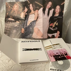 Antifragile - LE SSERAFIM - Säljer LE SSERAFIMs andra mini-album 'Antifragile'. Inkluderar en CD, fotobok och posters med gruppens medlemmar. Omslaget är stilrent i vitt med guldiga detaljer och titeln i svart. Perfekt för fans av K-pop och samlare av musikmemorabilia! Jag har använt några klistermärken men inget annat inget Photocard medföljer, skriv ofall ni vill ha fler detaljer