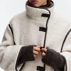 Vit teddyjacka med svarta detaljer - Supermysig vit teddyjacka med svarta kantdetaljer och knäppningar framtill. 