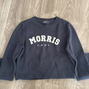 Svart tröja från Morris Lady - Säljer en snygg svart tröja från Morris Lady med vit text på bröstet. Tröjan har en klassisk rund hals och är perfekt för både vardag och lite finare tillfällen. Den är i bra skick och passar perfekt till jeans eller kjol. Perfekt för höst och vår!
