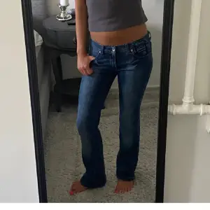 Säljer ett par snygga blå jeans i bra skick. De har en låg midja och en straight passform som ger en avslappnad look. Perfekta för vardagsbruk och kan matchas med nästan vad som helst. De är bekväma och stilrena, ett måste i garderoben!