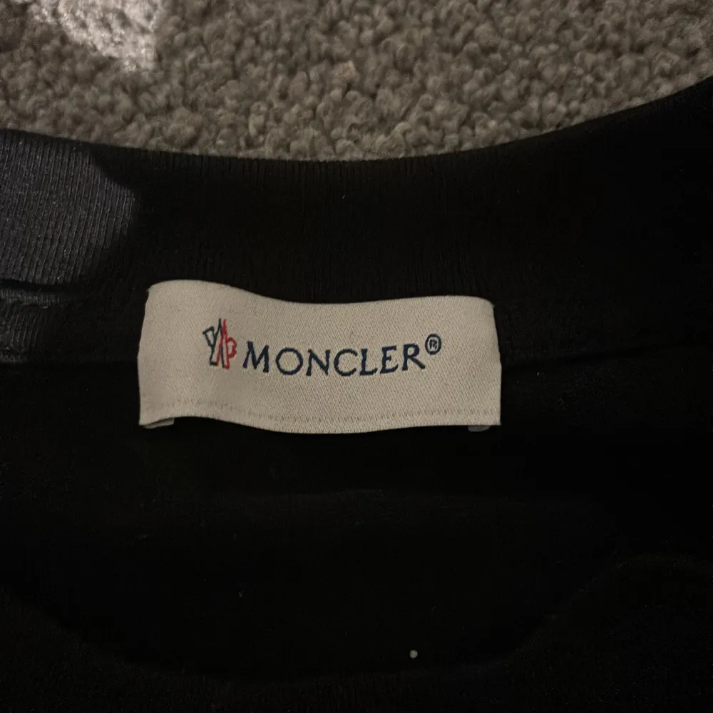 Säljer en svart t-shirt från Moncler i mycket bra skick. Den har en stor Moncler-logga tryckt på framsidan och är tillverkad i Italien. Perfekt för en stilren och avslappnad look.. T-shirts.