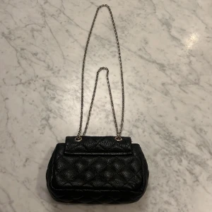 Svart quiltad handväska från Milk x Soda - Säljer en snygg svart quiltad handväska i skinn från Milk x Soda. Väskan har en elegant kedjerem och ett stilrent spänne framtill. Fräsch utanpå och inuti. Perfekt för både vardag och fest! INKÖPT PÅ LUCCA STHLM. NYPRIS 1200kr❤️