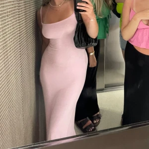 Ljusrosa långklänning - Säljer en superfin ljusrosa långklänning med smala axelband. Perfekt för sommarens fester eller en mysig kväll ute. Klänningen har en tight passform som framhäver figuren. Den är gjord i ett mjukt och bekvämt material.