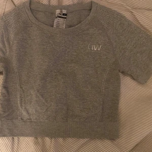 ICIW träningstopp - Croppad grå träningstshirt från ICIW. Nypris 399 kr. Texten är lite sprucken på bokstäverna.