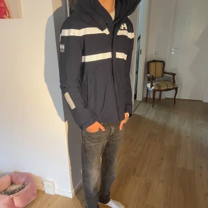 Helly Hansen vindjacka  - Väldigt bra skick. Som i ny skick. Nypris 3000kr. Säljer nu då den inte kommer till andvändnig. Hör av er vid frågor!! Killen på bilden 183cm 