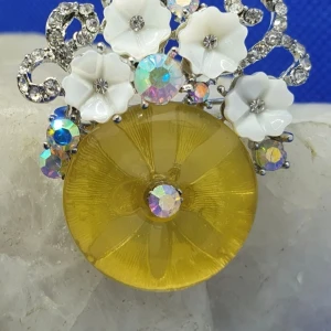 Vacker brosch/hänge med små blommor - Den här broschen med små vita blommor är ca 4 × 3.5 cm. Denna går även att använda som hänge till halsband då den har en ögla på baksidan. 