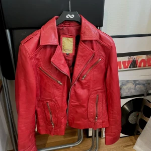 Röd skinnjacka med dragkedjor - Säljer en supercool röd skinnjacka från Avirex. Den har flera dragkedjor och detaljer. Jackan är i bra skick och perfekt för att ge din outfit lite extra färg. Passar perfekt till både vardag och fest! Står storlek XL men passar bra på mig är S/M