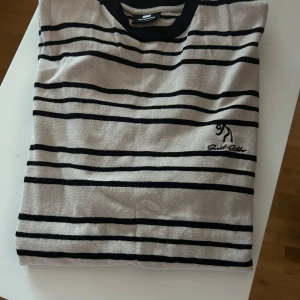 T-shirt - Fin oanvänd t-shirt. Beige botten med svarta ränder.