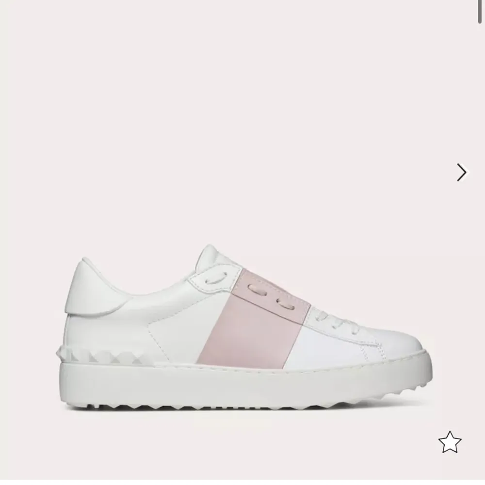 Snygga vita Valentinos  med en bred rosa rem över mitten. Skorna har en cool och modern design med en platt sula och små nitar runt hälen. Perfekta för en avslappnad och stilren look. ( Skriv om mer bilder 💕💕). Skor.