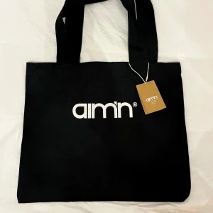 Aim’n tygväska - Oanvänd tygväska från ami’n. Det står ami’n på båda sidorna. Detta kan man se på bilderna.  Bredd 42 cm/ Höjd 35 cm Rök och djurfritt hem. 