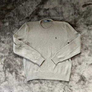 Ralph Lauren tröja - Säljer snygg stickad Ralph Lauren tröja i storlek S. Den är i bra skick av färgen grå. Mått finns på bild så slipper ni fråga om passform😊