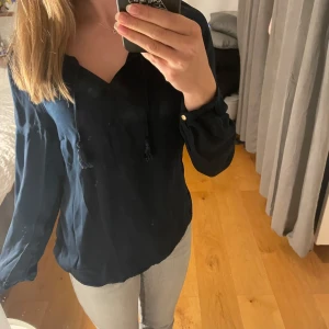 Marinblå blus - Blus med tofsar, man kan knyta den fram om man vill, syns på bilden. Bra skick, inga synliga defekter. Kvar tills markerad som såld❤️ storlek 38/S