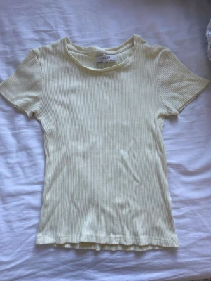 Ribbad ljusgul t-shirt från Lindex - Jättefin ljusgul t-shirt från Lindex Ribbad modell med figurnära passform som sitter superflott! Den ljusgula färgen är perfekt till vår och sommar och passar till allt  Använd endast ett fåtal gånger – i mycket fint skick