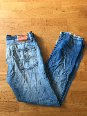 Levi's 513 ljusblå jeans - Säljer ett par klassiska Levi's 513 jeans i ljusblå denim. Modellen har rak passform och fem fickor, med den ikoniska läderlappen bak i midjan. Perfekta för en avslappnad och trendig look. Passar dig som gillar tidlös streetstyle.