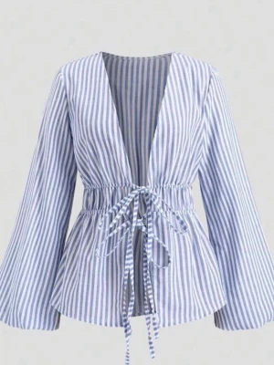Blåvit randig blus med knytband - Trendig blus med blå och vita vertikala ränder, djup V-ringning och knytband i midjan. Blusen har långa, lätt utsvängda ärmar och smockad midja för en snygg siluett. Tillverkad i ett lätt bomullsliknande material som känns fräscht och luftigt.