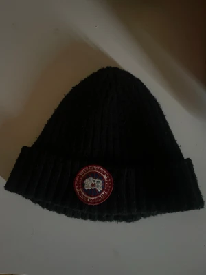 Canada Goose Mössa - Simpel och väldigt snygg mössa. Osäker om den är äkta då den vart en present. Aldrig sett någonstans.