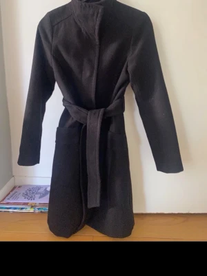 Svart klassisk kappa med skärp - Stilren svart kappa med hög krage och knytskärp i midjan. Har super fina guldiga knappar!  Enkel att matcha med olika outfits. ❤️