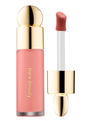 Rare Beauty flytande rouge i rosa - Flytande rouge från Rare Beauty i en mjuk rosa nyans. Kommer i en stilren glasflaska med guldfärgat lock och applikator för enkel applicering. Perfekt för att ge kinderna en fräsch och naturlig look.