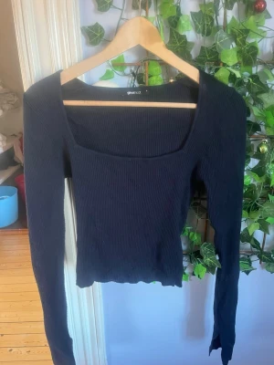 Svart ribbad topp Gina Tricot - Trendig svart ribbad topp från Gina Tricot med lång ärm och fyrkantig urringning. Den här slit i armarna. Har haft ett tag men inte använt jätteofta så märker inga riktiga problem med den förutom möjliga noppror 