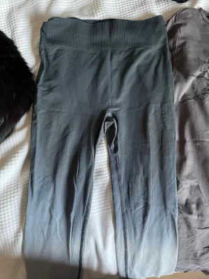 Grå ombre leggings från 157 Funk - Snygga grå leggings från 157 Funk med ombre-effekt som går från mörkgrå upptill till ljusare grå nedtill. Hög midja med bred ribbad linning för extra komfort. Perfekta till träning eller chill. Materialet är stretchigt och följsamt.