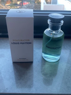 Louis V Imagination parfym 100 ml - Lyxig parfym från Louis V Imagination, i en stilren glasflaska med svart lock och transparent blå vätska. Flaskan rymmer 100 ml och kommer med originalförpackning i vitt. Perfekt för dig som vill ha en exklusiv doft i snygg design.