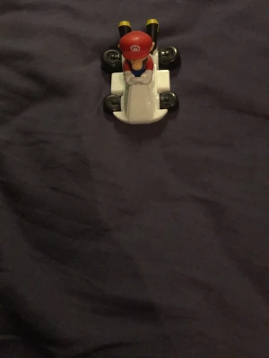 Vit mario leksaksbil i plast - Säljer en liten vit leksaksbil med svarta hjul. Bilen är tillverkad i plast och har en klassisk form. Perfekt för dig som gillar samlarbilar eller vill ha en rolig detalj till rummet.